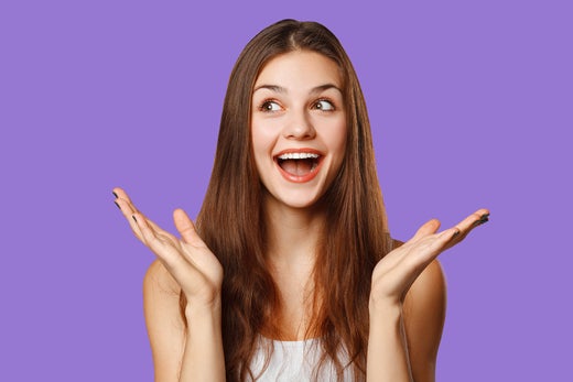 Surprised and happy girl on purple background